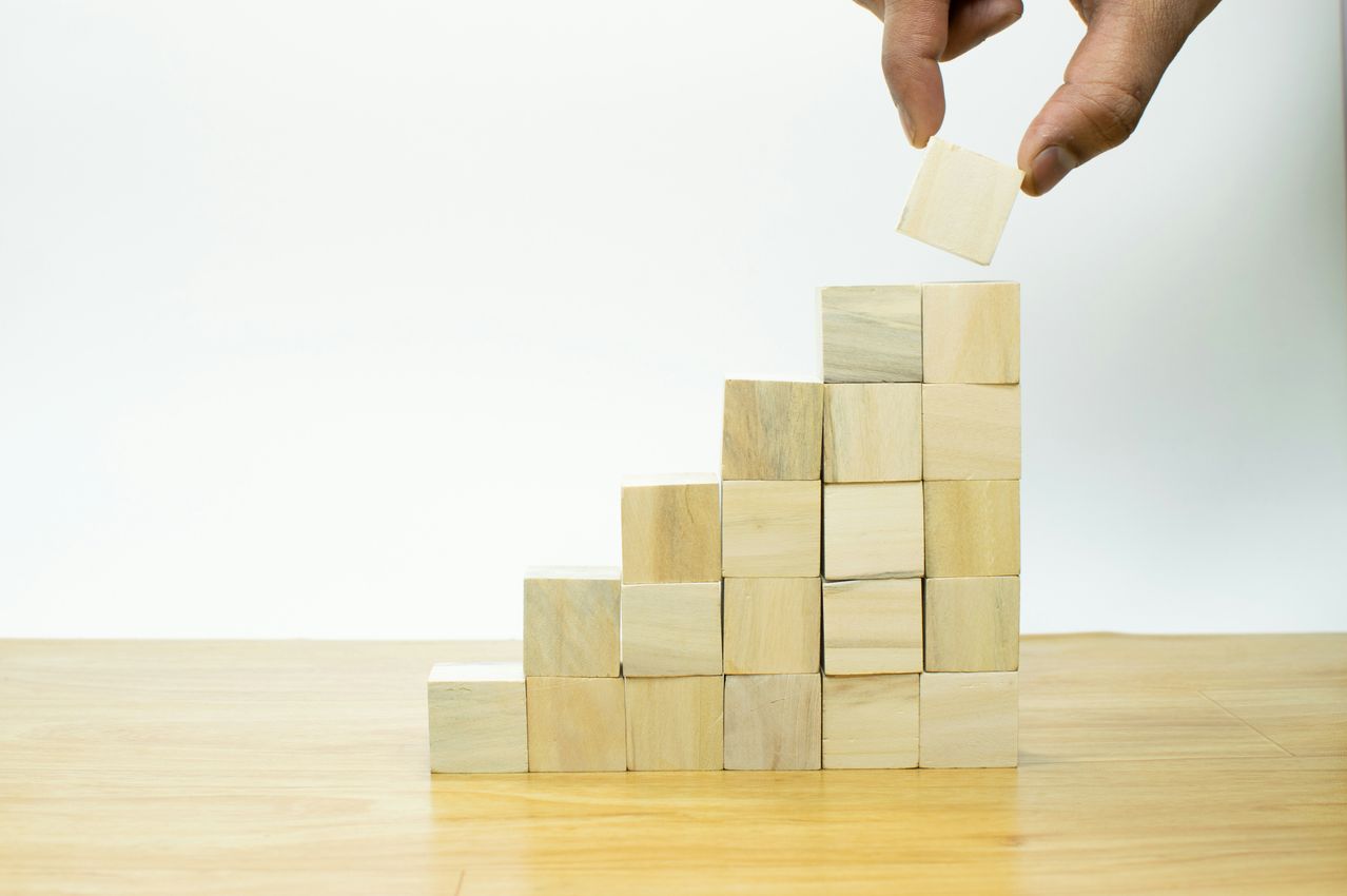 Hand stacking blocks to represent business growth planning